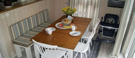 A dining area with a wooden table, white chairs, a bench, and a small rug.