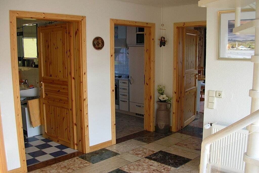 Un couloir avec des portes en bois donnant sur une cuisine et une salle de bain.