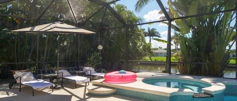 A pool area with lounge chairs, a hot tub, and a covered section with a glass ceiling.