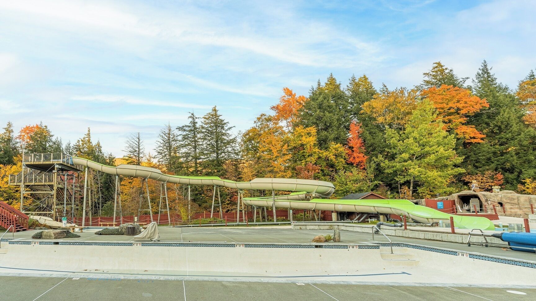 A water park with a long water slide, a pool, and a wooden deck area.