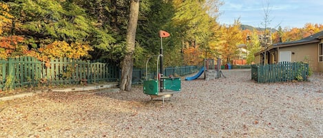 Un parque infantil con tobogán, estructuras para escalar y una zona vallada.