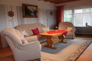A living room with a sofa, armchairs, a wooden coffee table, and a painting on the wall. - Holiday apartment with 2 bedrooms (Norden-Norddeich)