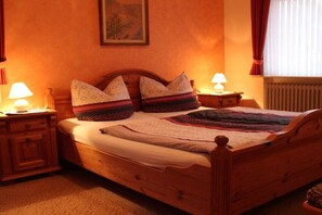 Un lit en bois avec une tête de lit, deux tables de chevet avec des lampes, une courtepointe et un tableau encadré accroché au mur.