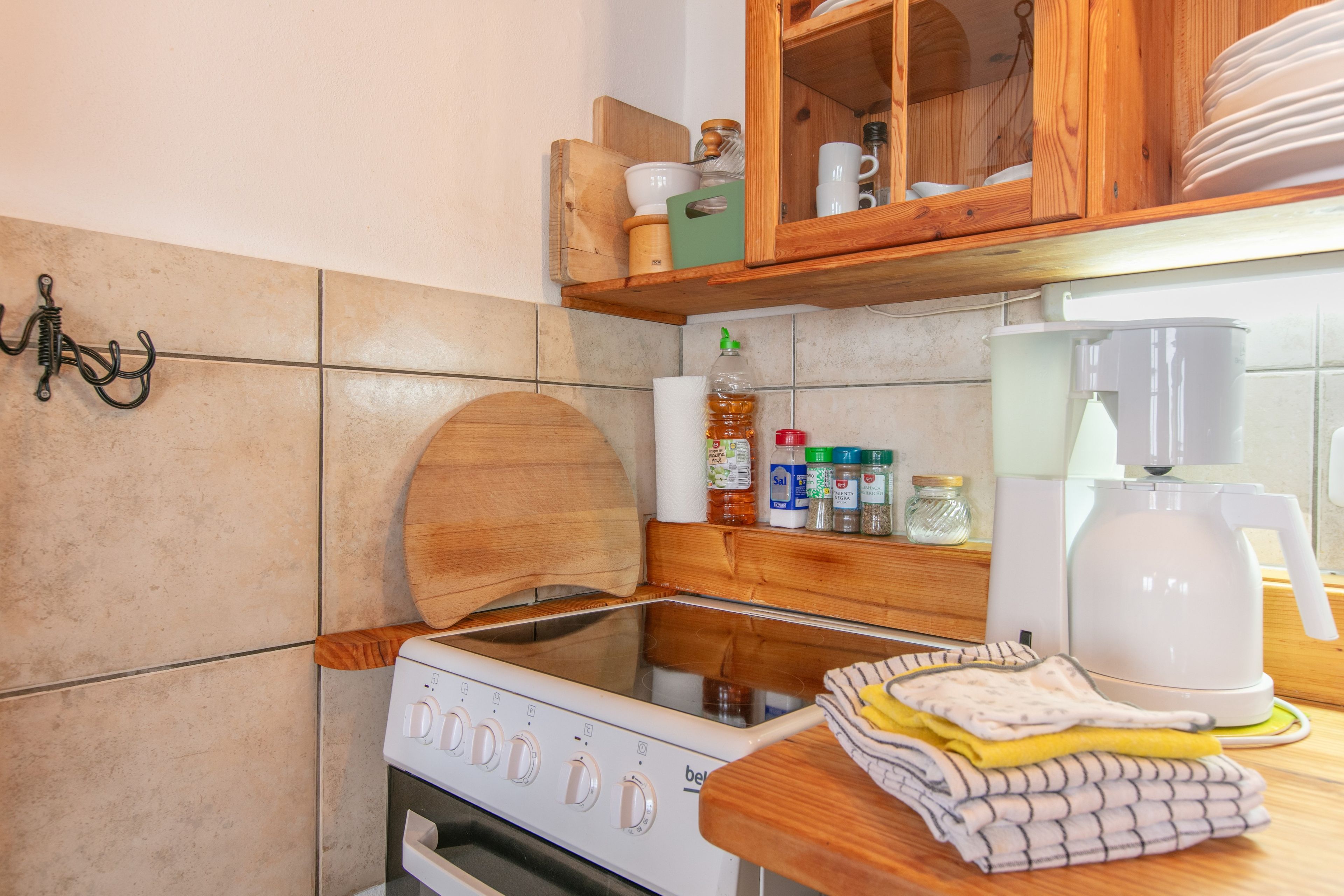 A kitchen with a stove, a coffee maker, and various kitchen items on the counter.