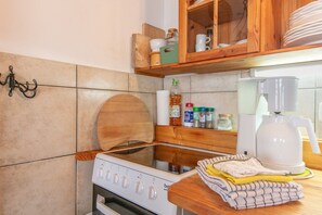 Een keuken met een fornuis, een koffiezetapparaat en diverse keukengerei op het aanrecht.