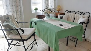 A dining area with a green tablecloth, white cushioned chairs, a bowl, a vase with flowers, and a wine glass. - Holiday Apartment for 3 People (59 m²) in La Sabinita with Sea View (La Sabinita)