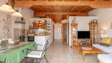 A spacious living area with a dining table, a sofa, and a television.