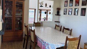 Une salle à manger avec une table en bois, des chaises, un buffet et une fenêtre donnant sur un beau paysage.
