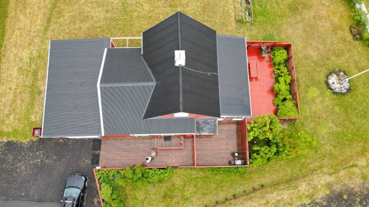 A two-story house with a red deck and a black roof.