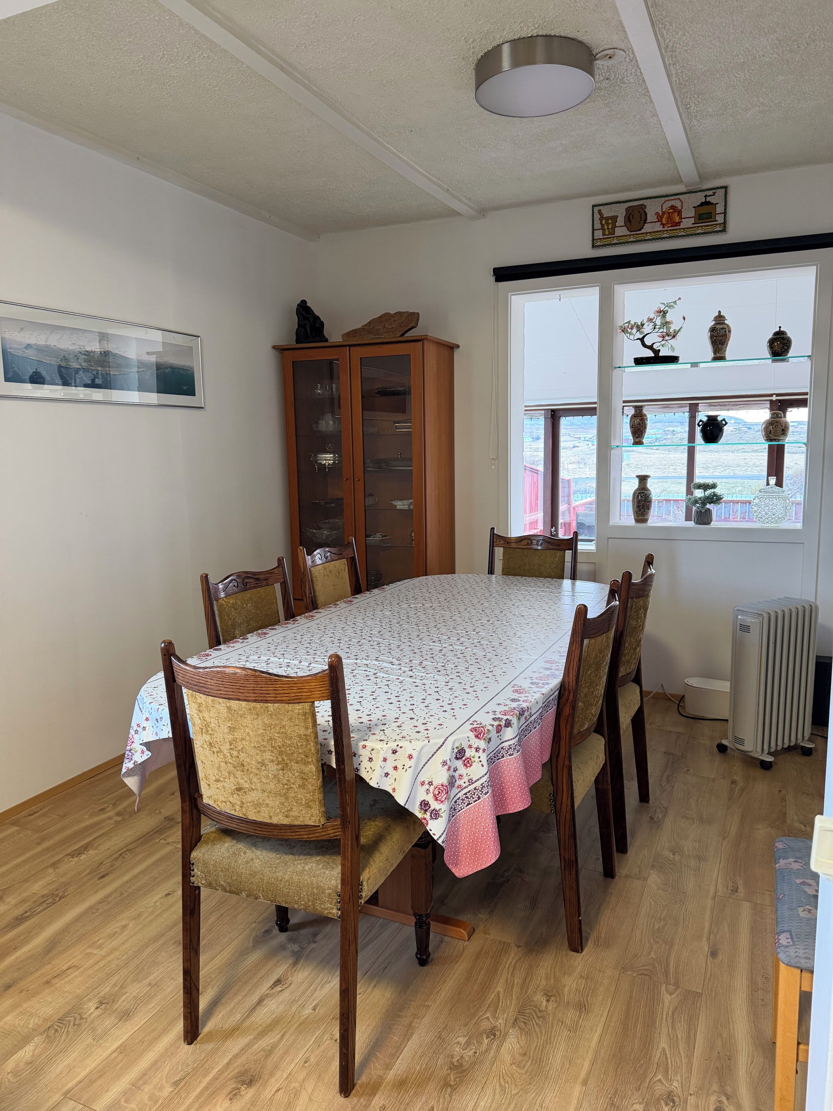 Comedor con mesa y sillas de madera, un aparador y una ventana con estantes.
