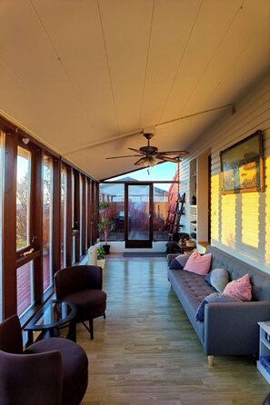 A spacious room with a ceiling fan, a sofa, a chair, and a table.