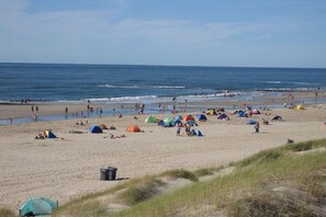 Una playa con tiendas de campaña y gente.