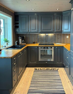 A modern kitchen with dark cabinetry, a wooden countertop, and a stainless steel oven. - Mountain cabin on Glåmhaugen with terrace (Svingvold)