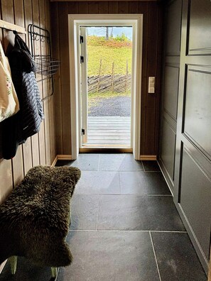 A wooden interior hallway leading to a glass door with a view of a grassy area. - Mountain cabin on Glåmhaugen with terrace (Svingvold)