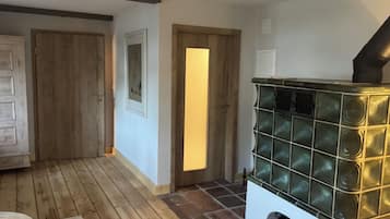 A room with a wooden floor, a fireplace with a glass front, and a door leading to another room.
