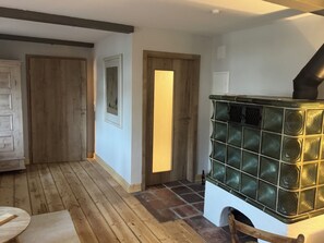 Une pièce dotée d’un plancher en bois, d’une cheminée avec une façade en verre et d’une porte donnant sur une autre pièce.