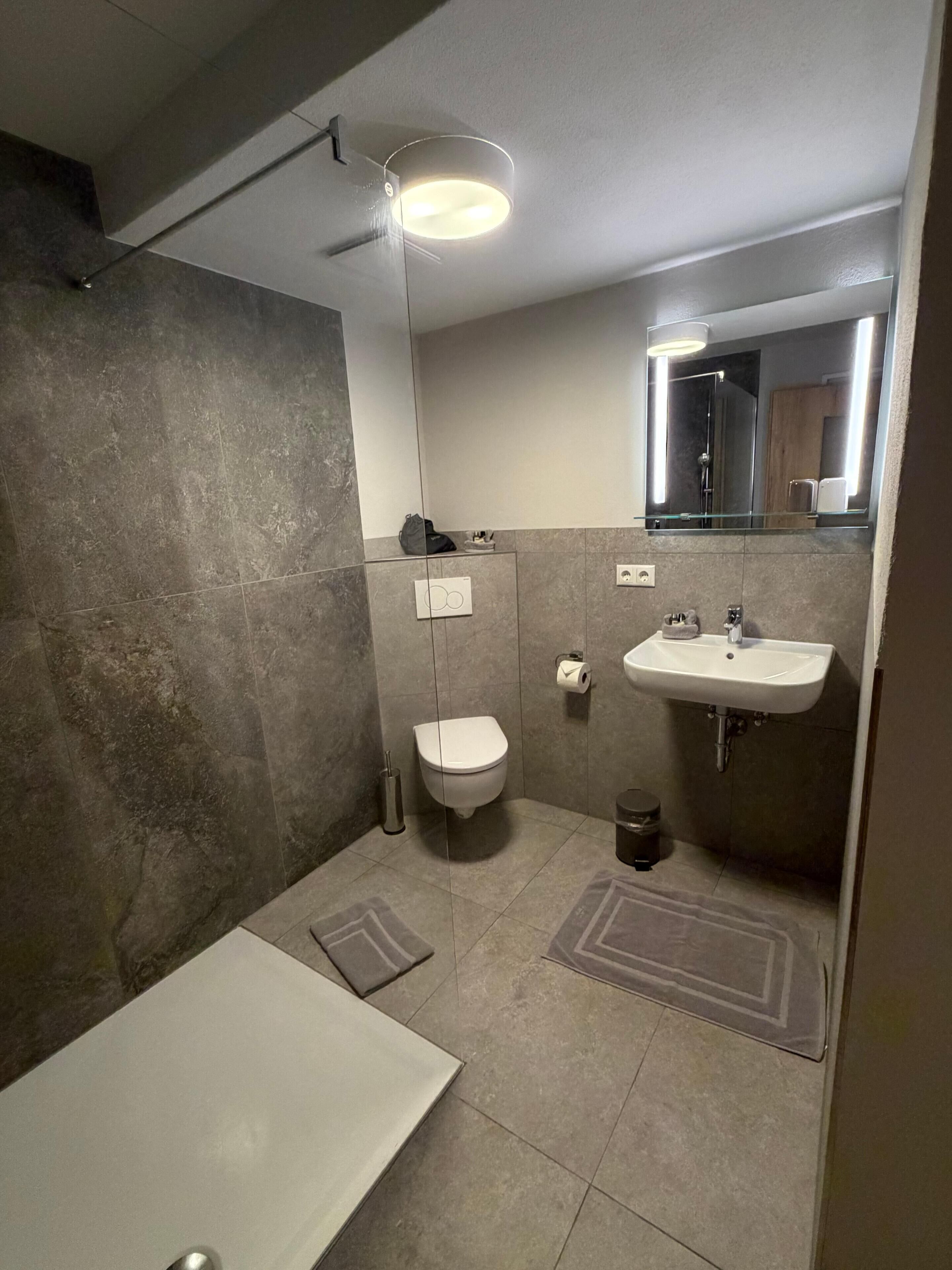Une salle de bain moderne équipée de toilettes, d’un lavabo et d’une douche.