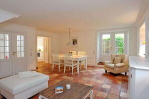 Ein Zimmer mit Esstisch, Stühlen, einer Couch und einem Fenster.