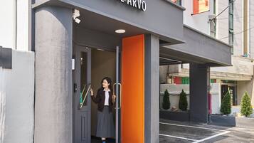 Entrada de hotel con diseño moderno, que incluye un puerta de cristal y un llamativo muro naranja.