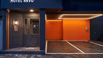 A hotel entrance with a dark facade, a glass door, and a sign indicating room number 109-16.