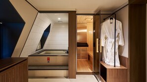 A modern bathroom with a glass shower enclosure, wooden flooring, and a robe rack.