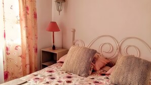 Ein Bett mit Blumendekor, eine rote Lampe auf einem Nachttisch und eine Wandleuchte.