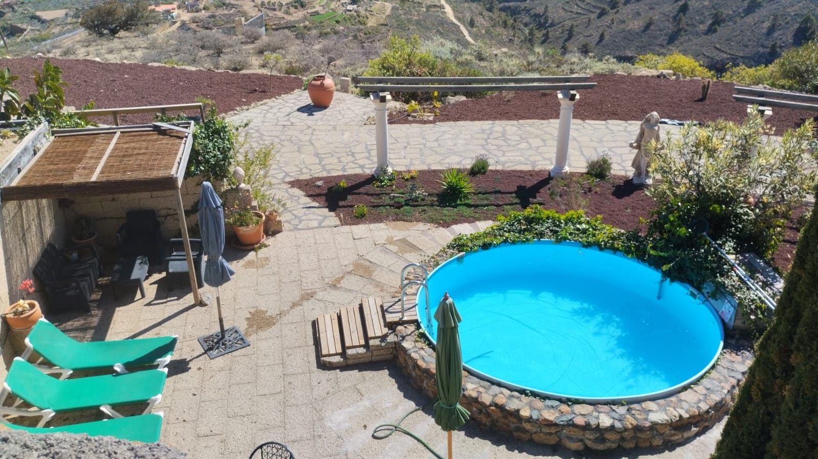 A backyard with a swimming pool, a patio area, and a garden.