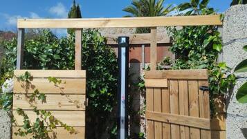 A wooden gate with a metal gate opener, surrounded by greenery.