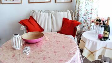 A dining area with a round table, a wooden bowl, a candle, and a bottle of champagne.
