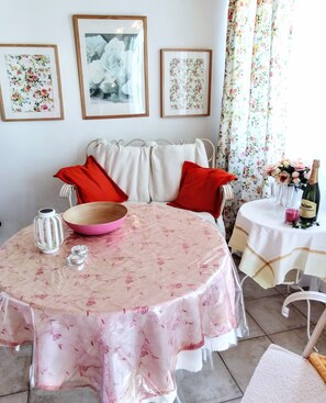 A dining area with a round table, a wooden bowl, a candle, and a bottle of champagne. - Casa Rosa – Charming Two-Bedroom Apartment with Panoramic Views (La Sabinita)