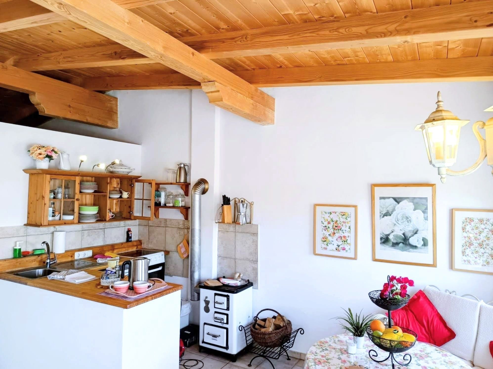A kitchen with wooden beams, a sink, a stove, and a dining area with a table and chairs.