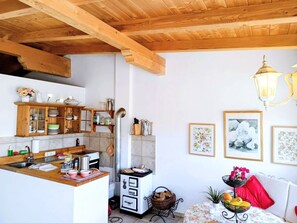 Cuina amb bigues de fusta, un rentaplat, una cuina i zona menjador amb taula i cadires.