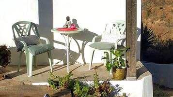 Een terras met een tafel en stoelen, omringd door potplanten en stenen.