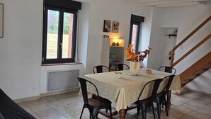 Un comedor con una mesa dispuesta para cuatro, una escalera y un ventanal con vistas.
