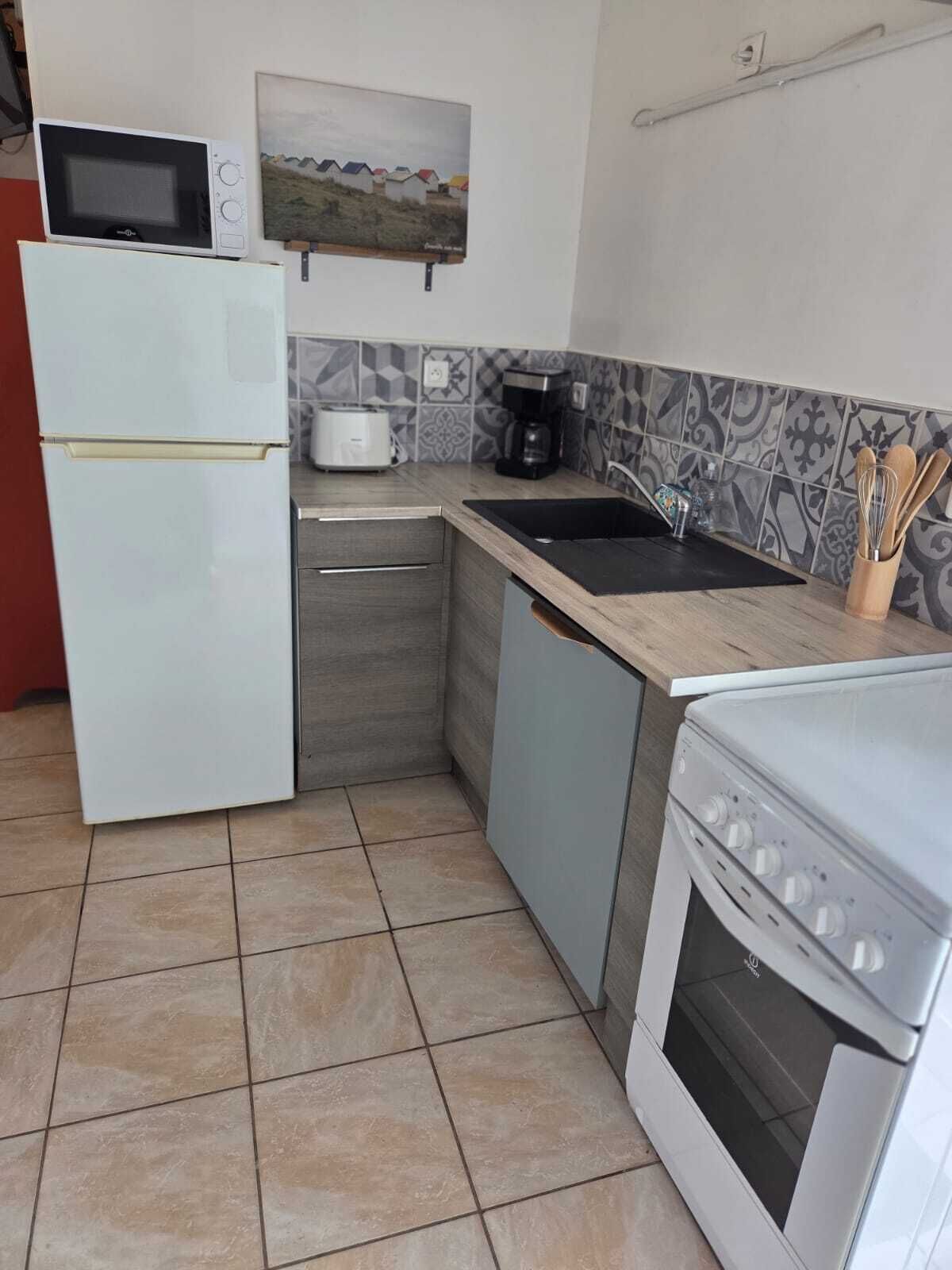 Eine kompakte Küche mit Kühlschrank, Mikrowelle, Kaffeemaschine und Herd.
