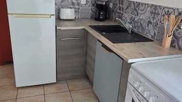 Eine kompakte Küche mit Kühlschrank, Mikrowelle, Kaffeemaschine und Herd.
