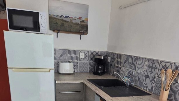 A compact kitchen with a refrigerator, a microwave, a coffee maker, and a stove.