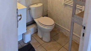 Un baño pequeño con inodoro, lavabo y un perchero para toallas.