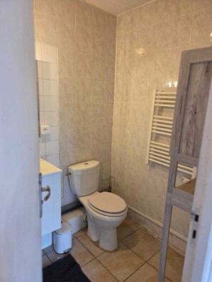 A small bathroom with a toilet, a sink, and a towel rack. - Vrbo Property (Terre-et-Marais)