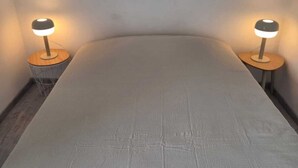Un dormitorio con una cama individual, dos mesitas de noche y dos lámparas fijadas a la pared.