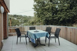 A balcony with a table and four chairs, surrounded by a wooden fence and trees. - Holiday home in Aach with swimming pool (Aach)