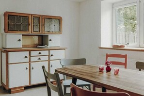 A dining area with a wooden table, white cabinets, and a window with a view of trees. - Holiday home in Aach with swimming pool (Aach)