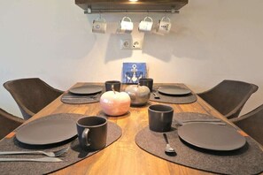 Een eettafel gedekt met borden, bestek en mokken, met een decoratieve appel als middelpunt.