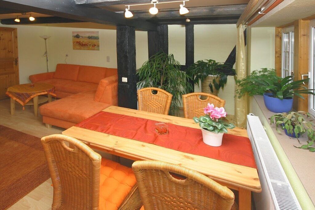 Un salon chaleureux avec un canapé, une table à manger et des chaises, ainsi que des plantes en pot.