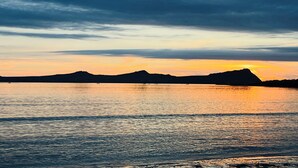 A sunset over a calm body of water with distant landforms. - Charming cottage on Mount Brandon,stunning unimpeded ocean views close to Dingle (Dingle)