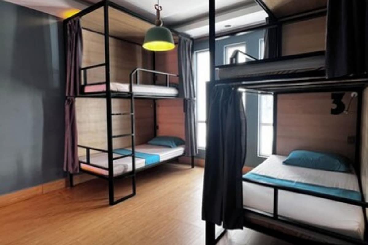 Un dormitorio con literas, una lámpara colgante y una ventana con cortinas.