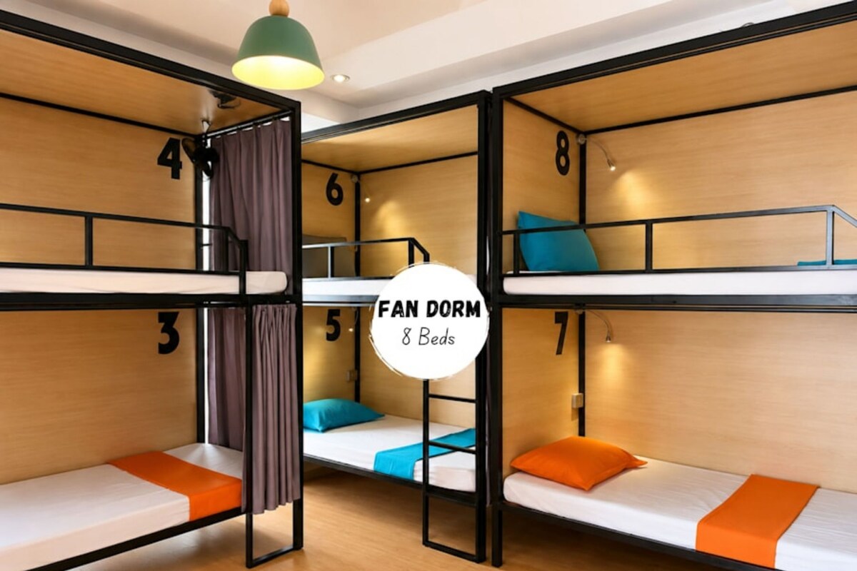Una camera del dormitorio con letti a castello, numerati da 3 a 8, e un cartello che indica 'Fan Dorm 8 Beds'.