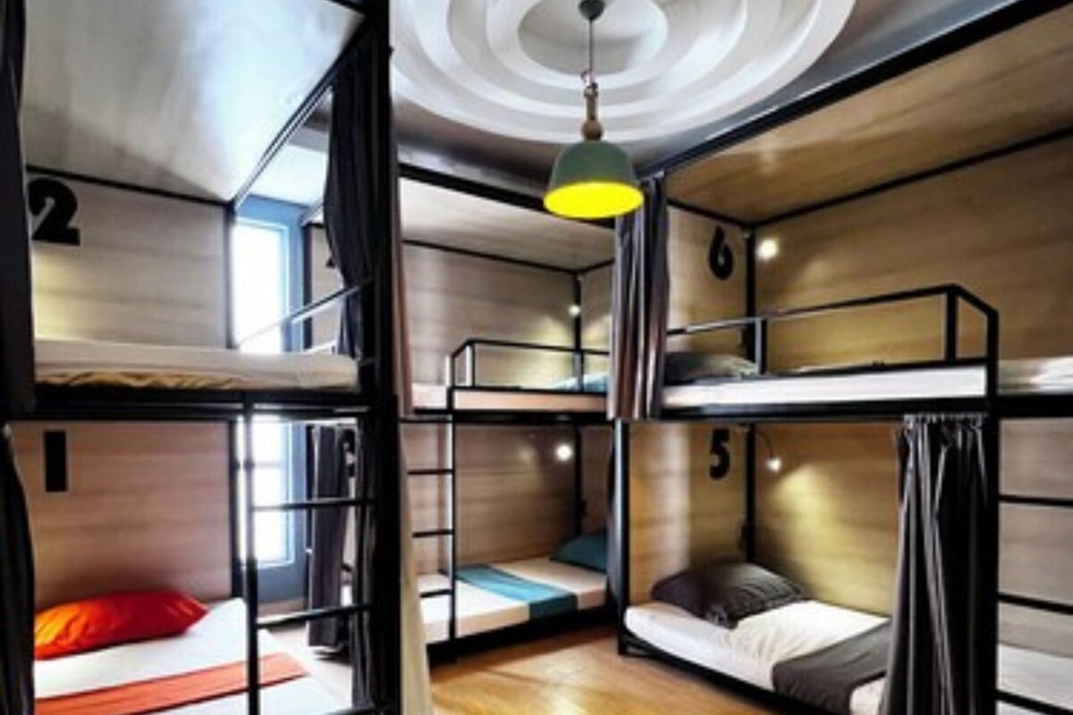Dormitorio con literas, piso de madera, diseño circular en el techo y lámpara colgante.