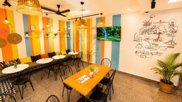 Un restaurant doté d’une longue table conviviale, de nombreuses chaises et d’un mur rayé aux couleurs vives.