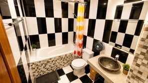 Un bagno con pavimento a scacchi, una vasca, un water e un lavandino.